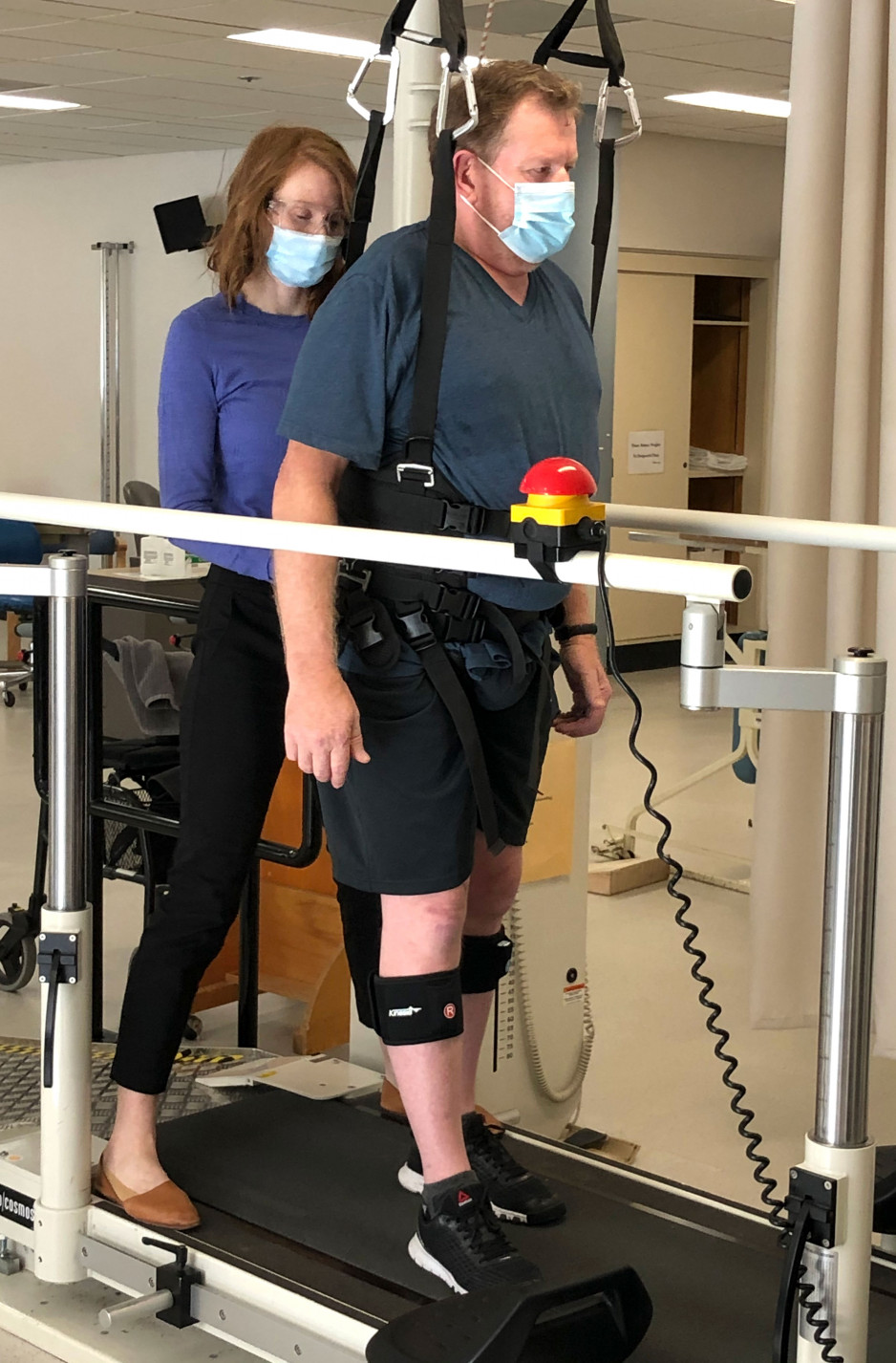 Paul Garrett suspended by a harness over a treadmill with a physiotherapist supporting him from behind