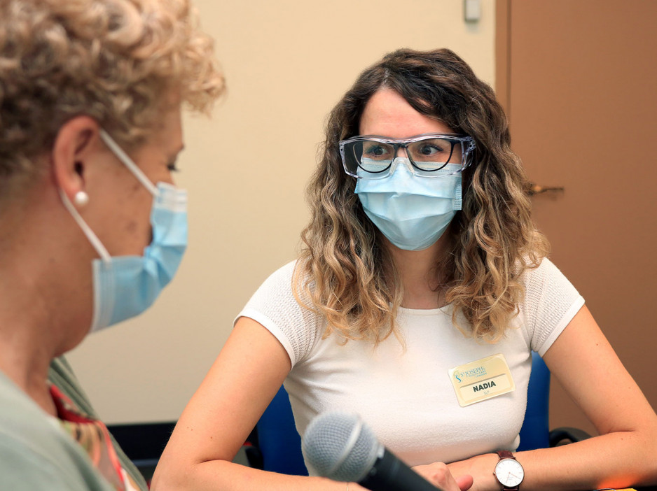 Nadia Torrieri wearing a mask looking toward her patient 
