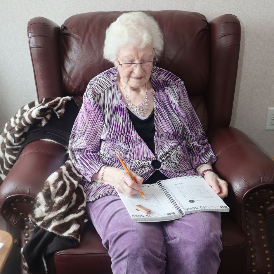 Maria sitting on a comfy chair working on a sudoku puzzle