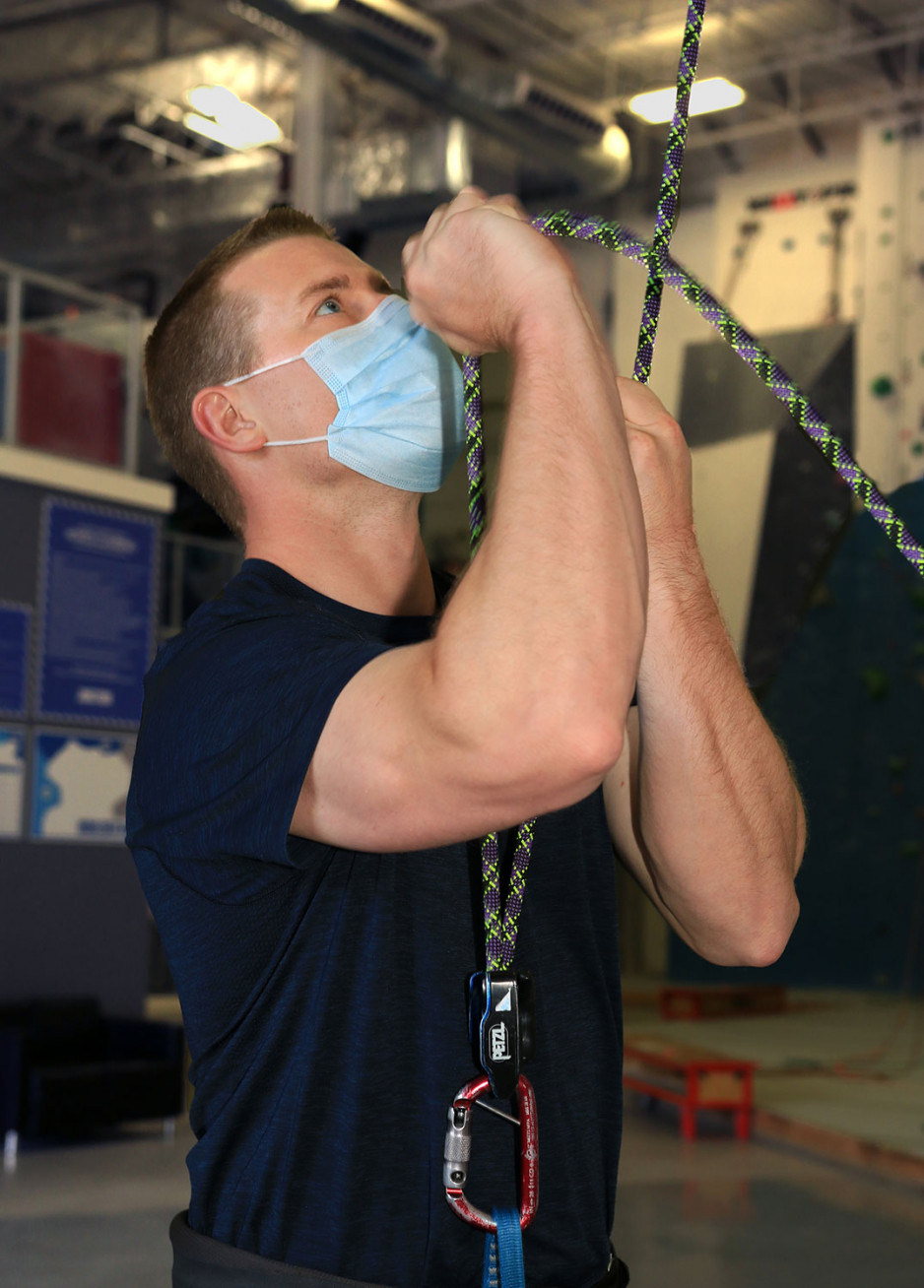 physiotherapist Neal McKinnon firmly holding the ropes that belay a climber on a climbing wall