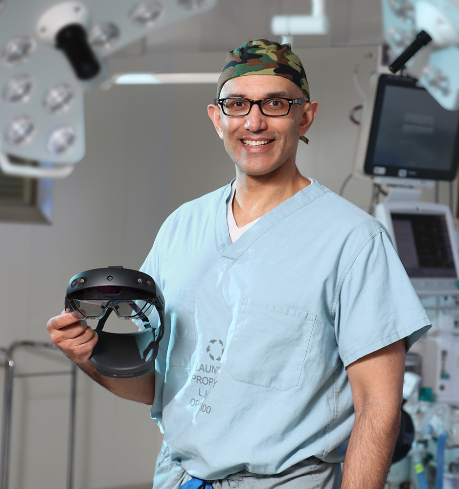 portrait of Dr. George Athwal standing in the operating room, wearing scrubs, holding a HoloLen2 headset