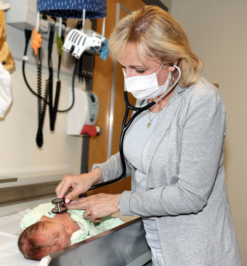 Dr. Laura Lyons listening to an infant's heart with a stethoscope