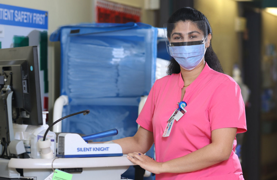 Jasmine Devassy wearing a pink nurses top, standing by a monitor at Parkwood Institute