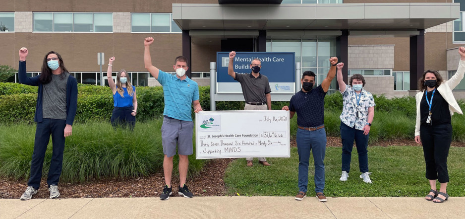 group holds up large vanity cheque and raising fists