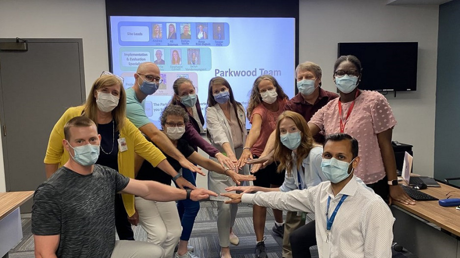 eleven members of the spinal cord injury care team reaching their hands together in a show of cooperation