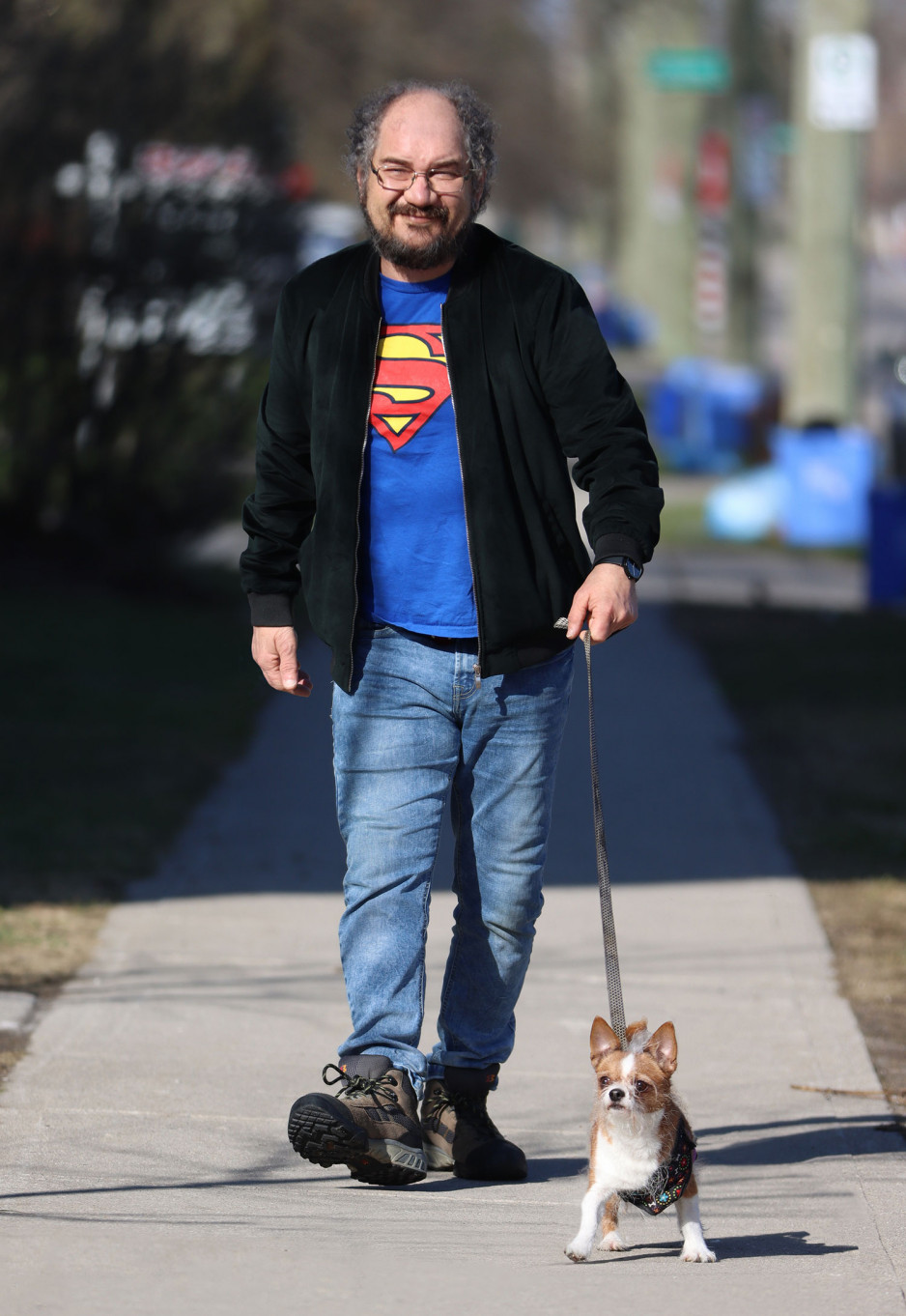 Mark Alfieri walking a small dog on the sidewalk on a spring day