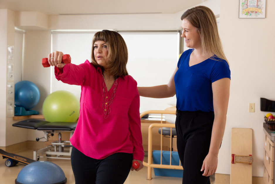 A woman lifts a dumbell with care provider's guidance