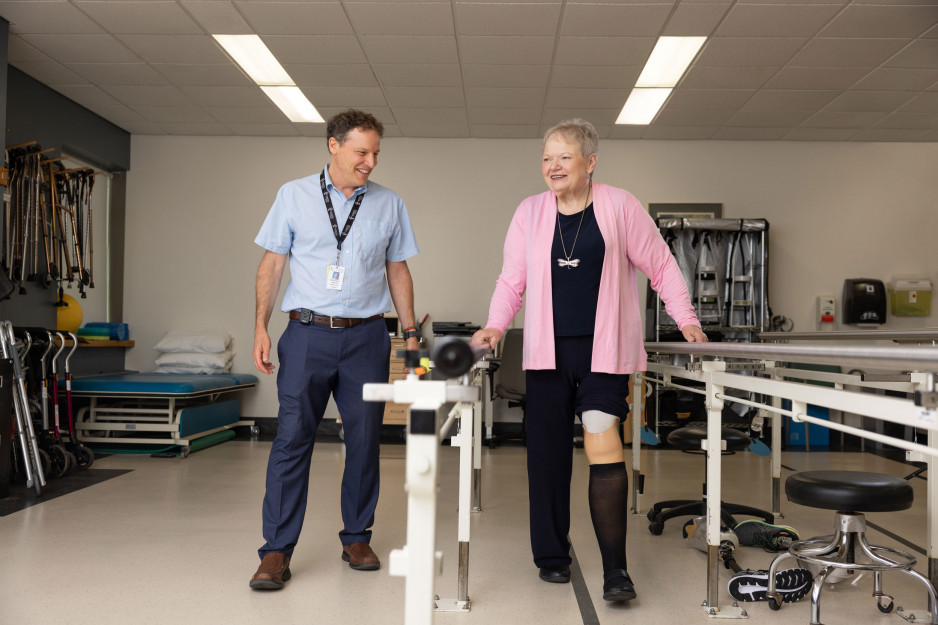 female patient using handrail to walk while physician observes
