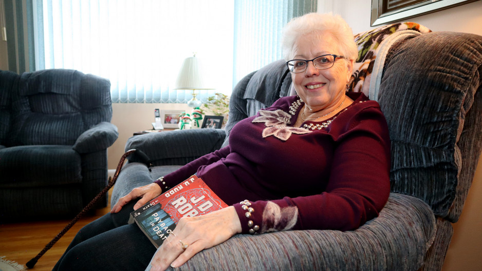 Lynda Vanderaa sitting in her home reading a book.