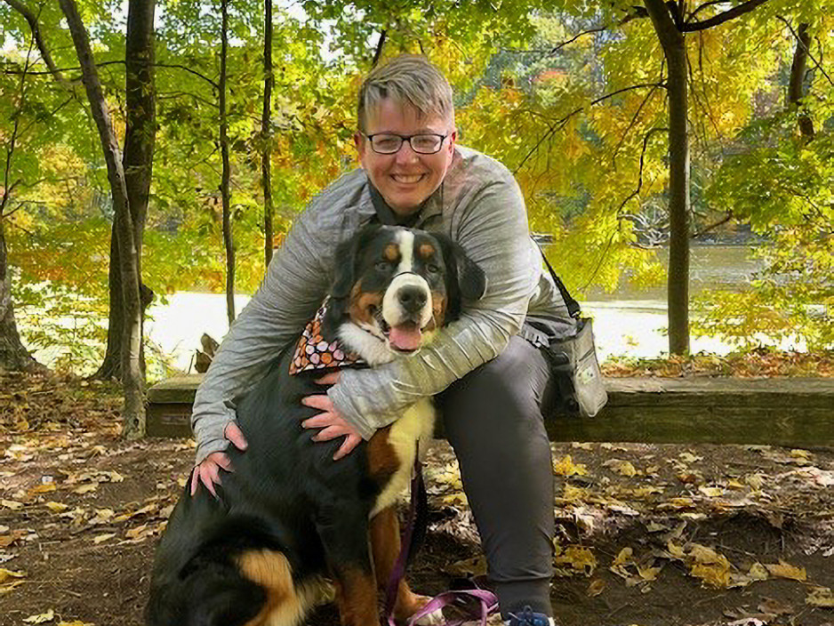 woman (Ashley Camden) hugging her dog in a forest