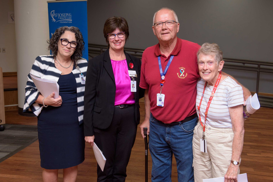 three women and one man stand together smiling