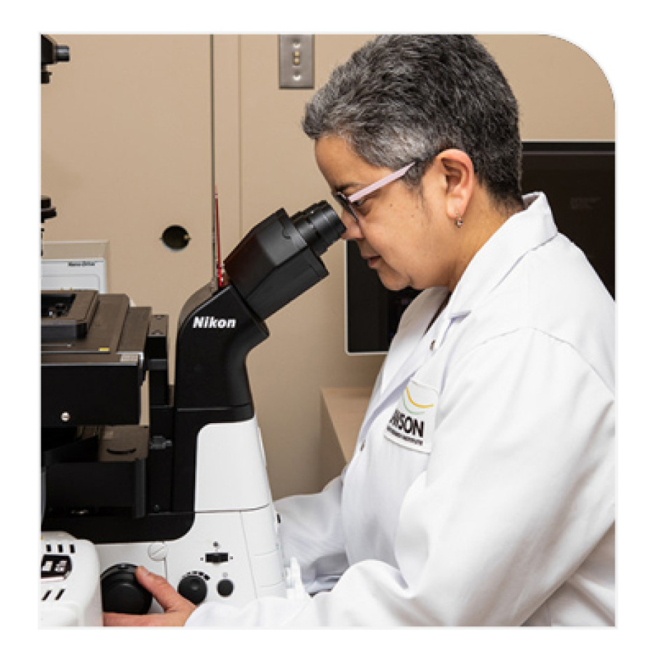 Savita Dhanvantari, PhD, looking at the microscope in a lab