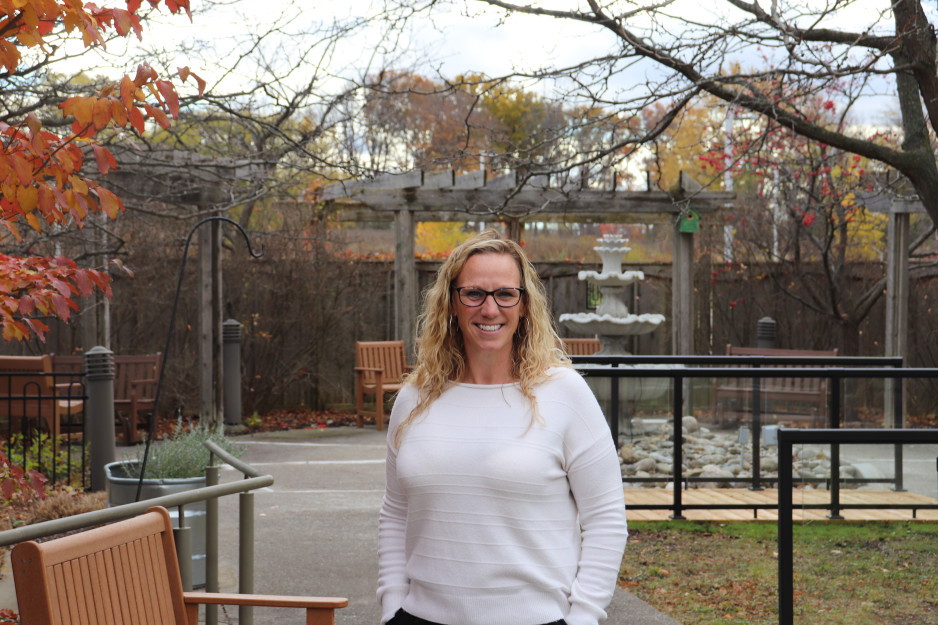 Jennifer Field in a white sweater stands in the renovated courtyard