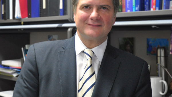 Dr. Manuel Montero-Odasso wearing a suite and tie, standing in front of a wall of books