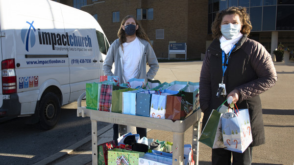 Stefan Nichol and staff Chaplain Jessica Baker unloading gifts from a van with an "Impact Church" sign on it