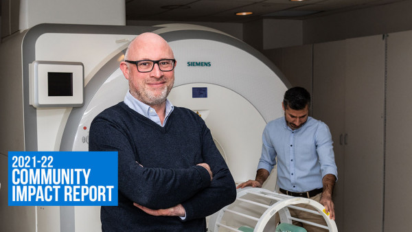 man with arms folded across body stands in front of MRI machine
