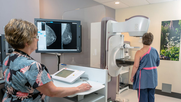 nurse performs mammogram on patient