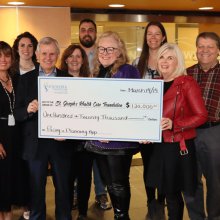 a group of people hold up a large cheque