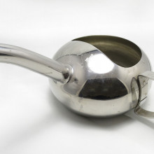 a silver feeding device that looks like a teapot with an extra-long spout