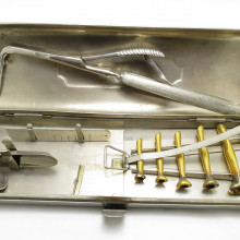 a set of historical medical tools used for intubation, all placed in a metal box