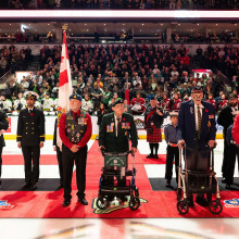 The veterans standing next to one another inside the the hockey rink