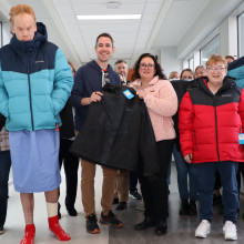 Group of people holding up coats donated by Columbia Sportswear