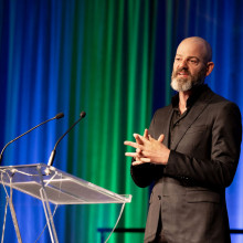 A man (Ryan Finch) standing on stage at a podium