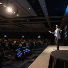 A man (Neil Pasricha) speaking to the audience in the ball room
