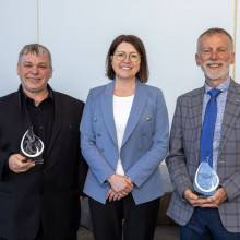 Three people standing beside each other with two people holding up their awards