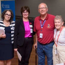 three women and a man standing together and smiling