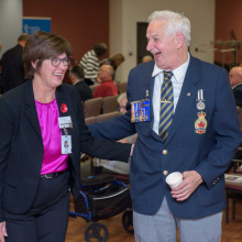 woman in purple shirt and man in uniform laugh together