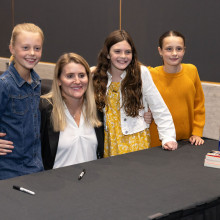 Hayley Wickenheiser poses with three little girls after signing their books
