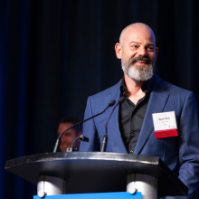 Man with beard speaking at podium