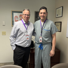 Two men stand together smiling in an office