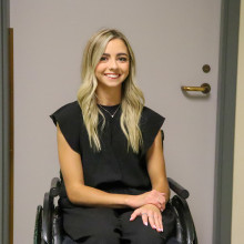 Sarah King, blonde and in black clothes, poses with a smile