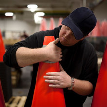 A man placing reflective tape to a stack of pylons