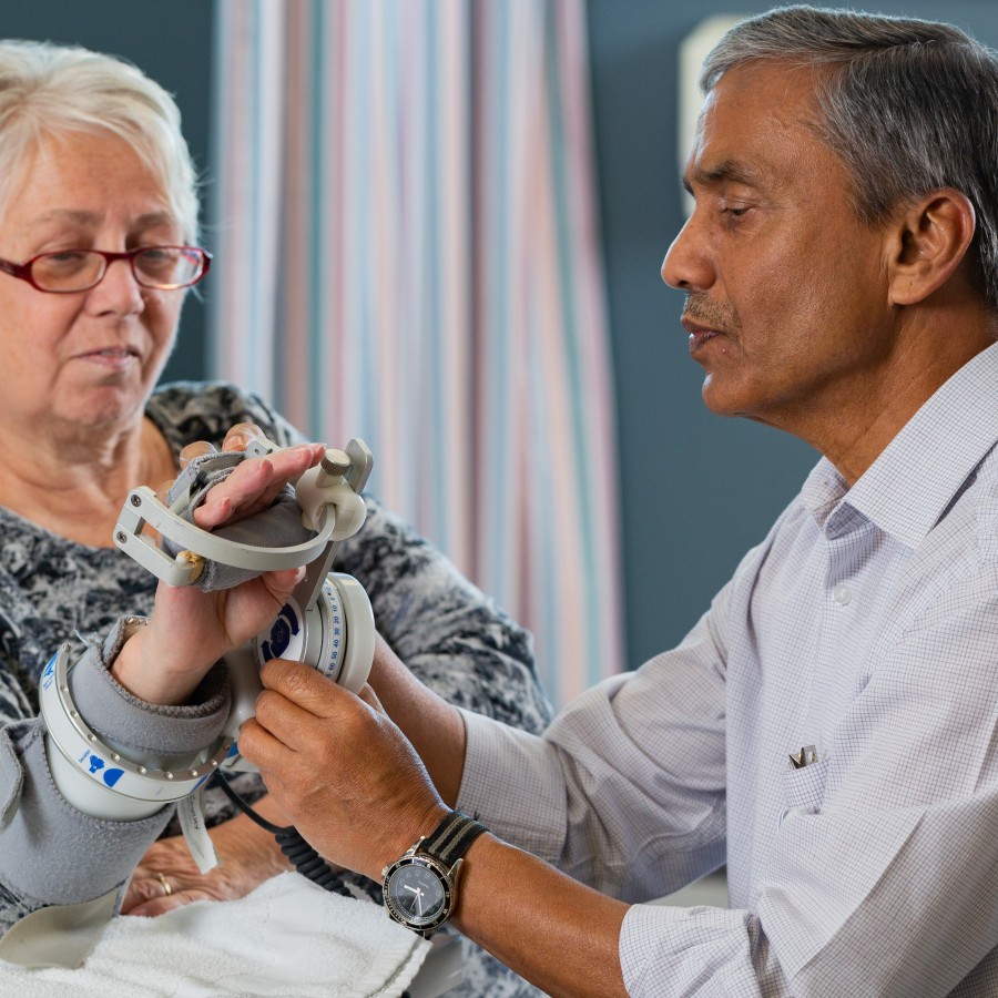 Image shows healthcare provider helping patient with a hand prosthetic.